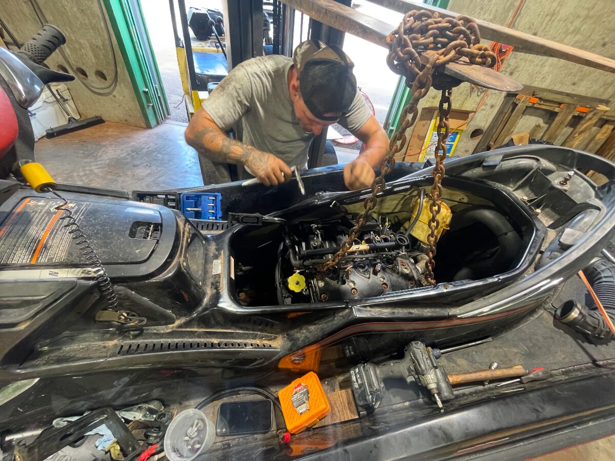 Technician working on a jet ski engine bay